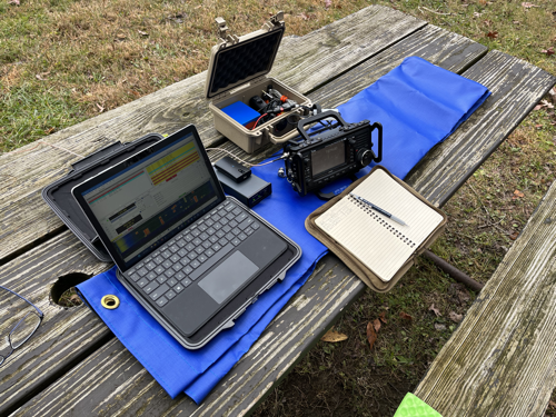 Surface Go 2, tuner, GPS, IC-705, Pelican case and notebook on a blue tarp.