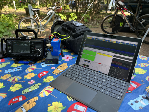 IC-705, tuner, battery, and MS Surface Go 2 on a decorative tablecloth.