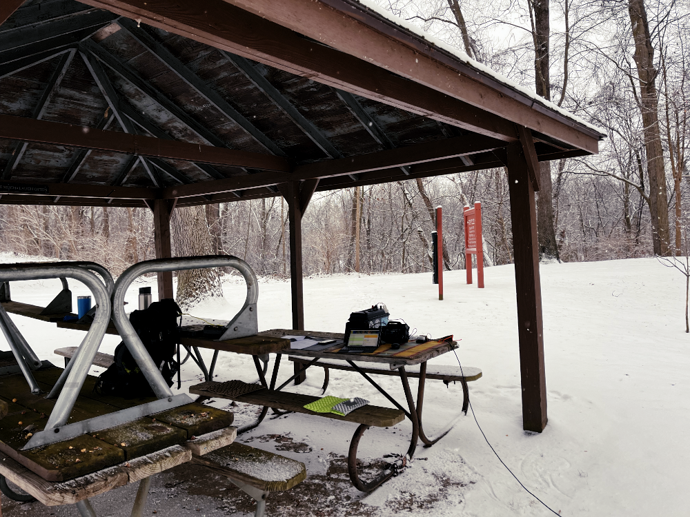 Our operating position in a winterized pavilion. There is radio equipment on the table and tables stacked on other tables for the winter.