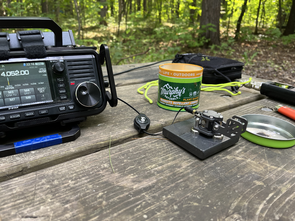 IC-705, Paddles, and citronella candel sitting on a picnic table in the woods of the Hiawatha National Forest. Not pictured: One Trillion Mosquitos.