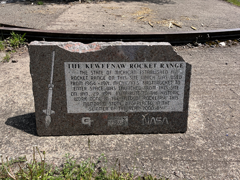 The official marker for the Keweenaw Rocket Range. It reads: The Keweenaw Rocket Range. The state of Michigan established a rocket range on this site which was used from 1964-1971. Michigan's first rocket to enter space was launched from this site on Jan. 29, 1971. In tribute to the historic work done in the field of rocketry, this memorial stone was placed in the summer of the yaer 2000 by GT, PFRCI, NASA.