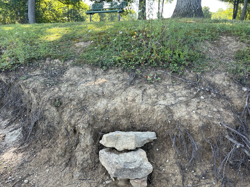 A couple of large rocks at the bottom of a large drop creating makeshift steps to the waterline.
