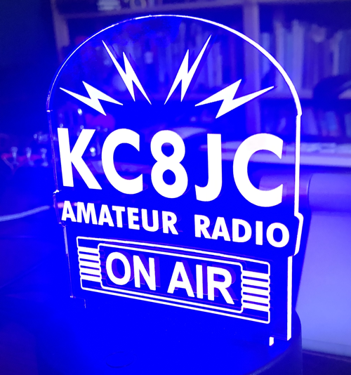An acrylic sign illuminated in blue light reading "KC8JC Amateur Radio ON AIR" - This was a great Xmas gift from my family!