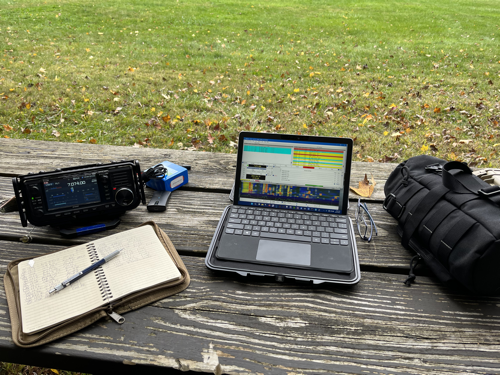 IC-705, notebook, laptop, and bag on a picnic table.