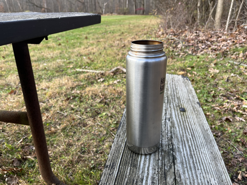 Thermal coffee cup on picnic bench.