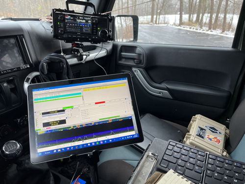 The setup inside of the Jeep: MS Surface GO 2 on a stand, IC-705, and Pelican case.