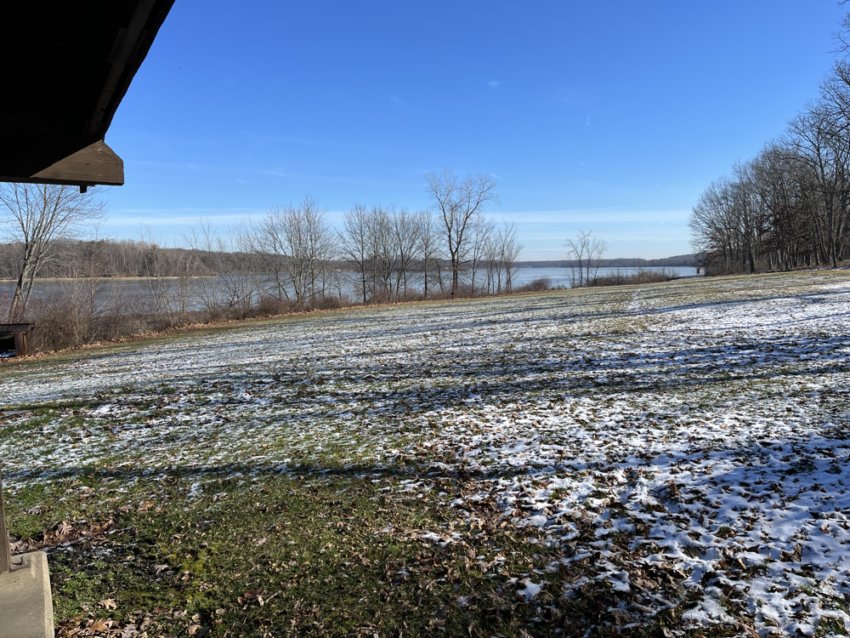 View of a snow crusted field leading to a lake in winter.