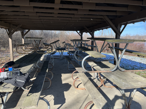 A pile of picnic tables in the pavilion. The park knows that winter usage is low in the winter so it stores the tables in the shelter to protect them from winter weather.