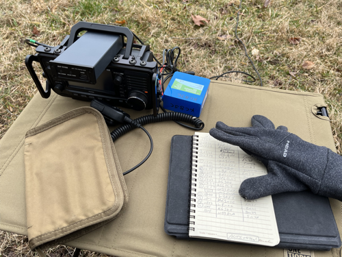 IC-705, ATU, Logbook, and Surface GO 2 sitting on a brown camp table.