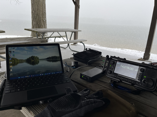 Surface GO 2 next to the IC-705 on a picnic table. The water is in the background and snow is falling.