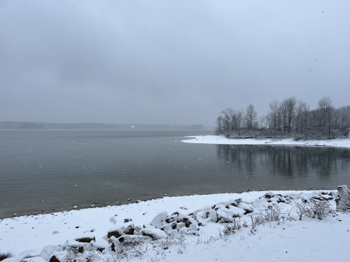A view of the reservoir from the edge of the picnic shelter. The shoreline is covered in snow.