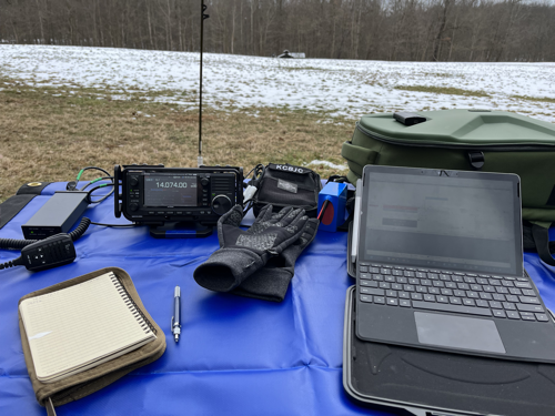 Radio and tablet set up on a blue tarp with Chameleon vertical antenna in the background.