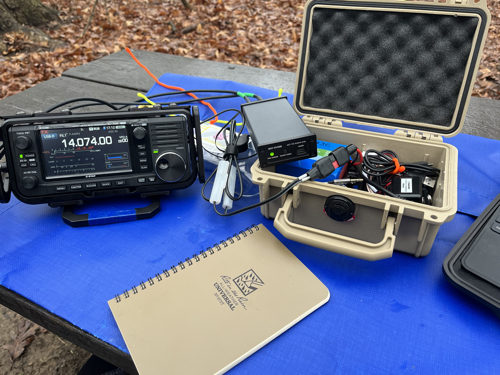 IC-705, Pelican Case, and notebook on a blue tarp.