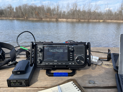 IC-705 and tuner on a picnic table with a pond in the background.