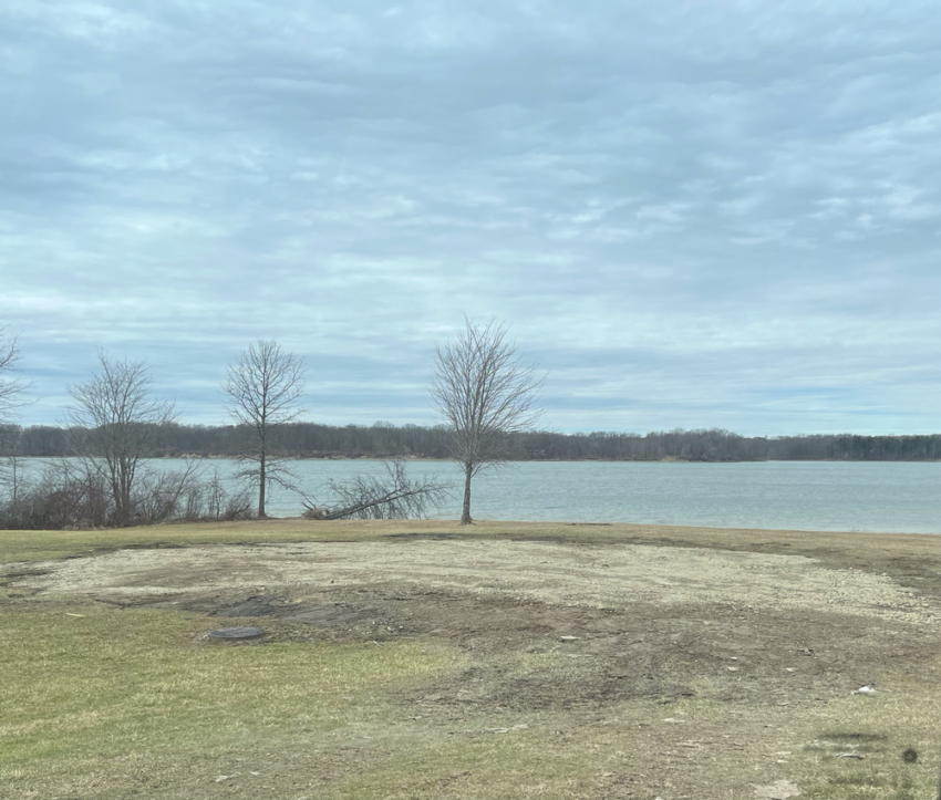 View of a reservoir with trees and a flat area where a park shelter used to be.