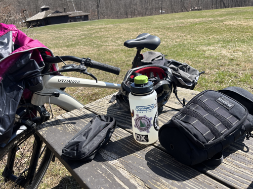 My bike leaning on the picnic table with my water bottle and gear bags.