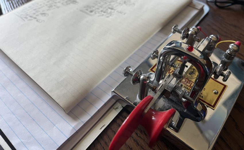 A Vibroplex key next to a notepad.