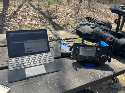 Surface Go 2 next to the IC-705 and mAT-705 tuner. Bags and bicycle in the background.