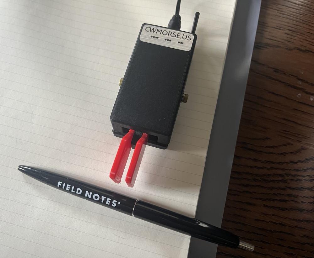 A CW Paddle with a Field Notes pen on a pad of paper.