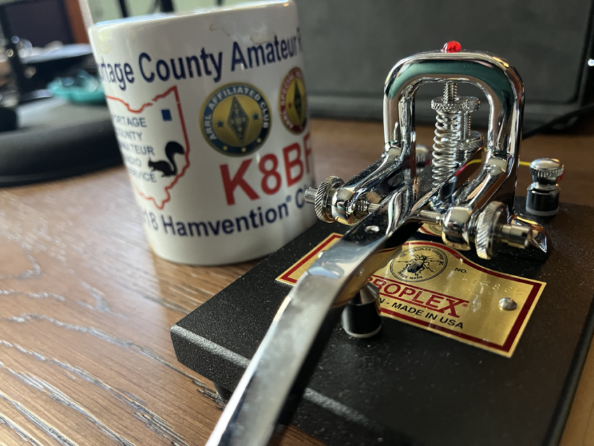 A coffee mug next to a Vibroplex straight key.