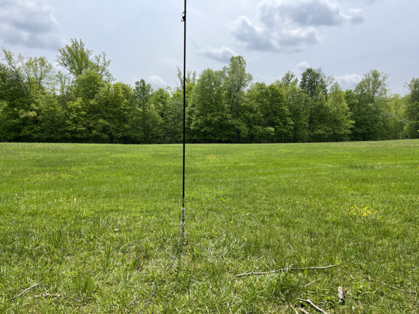 A vertical antenna in a green, grassy field.
