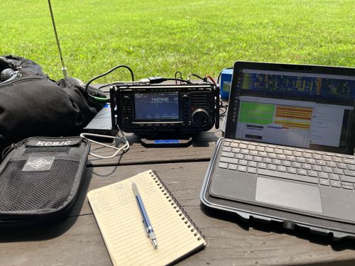 Gear pouch, IC-705, tablet, and notebook on a picnic table.