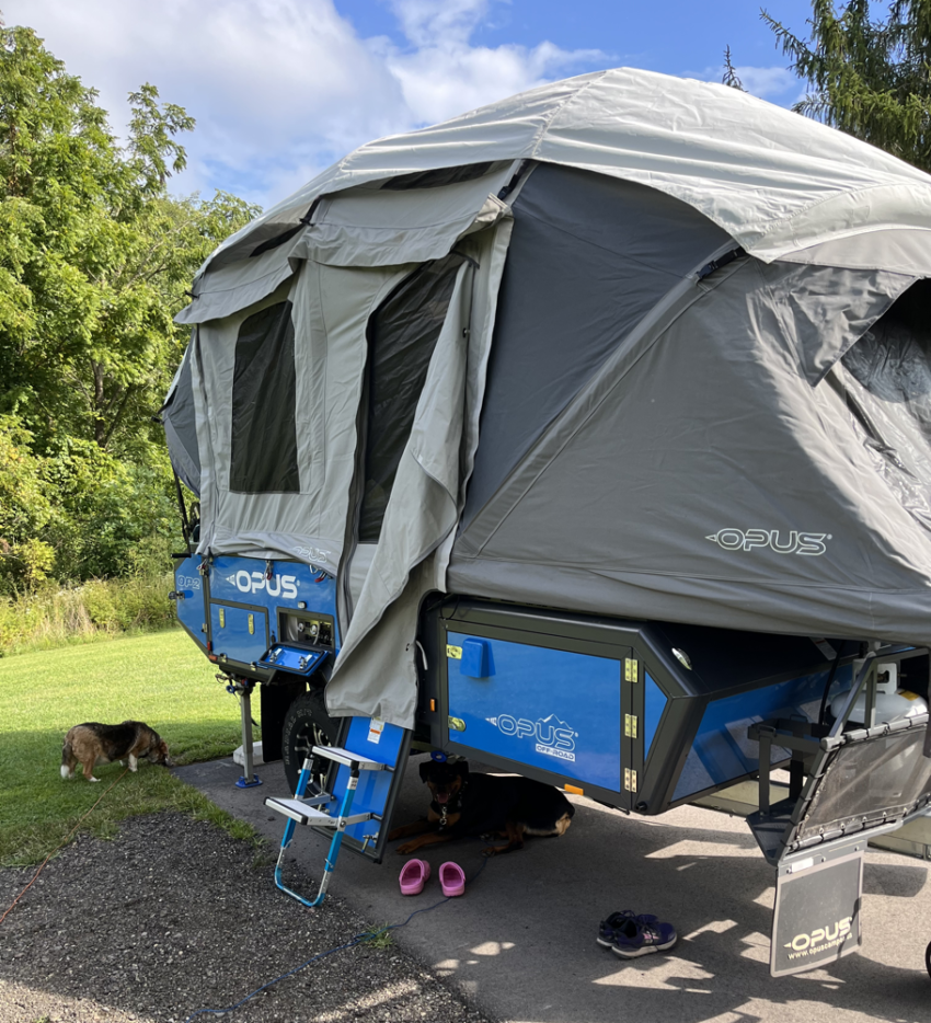Opus OP2 Camper set up at a campsite with a beagle next to it.