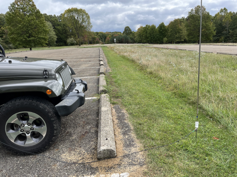 Vertical whip set up in the grass at the front of the Jeep.