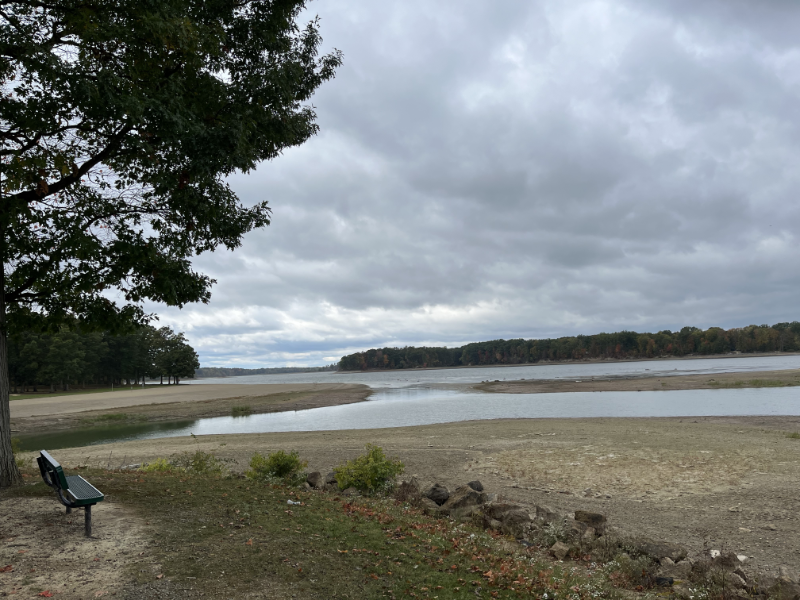 View of the reservoir with a park bench in the foreground. The sky is dark and the water is agitated by the wind.