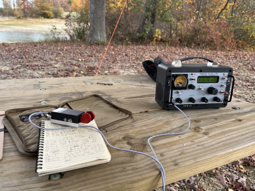 Log book with paddles resting on it next to a Penntek TR-45L radio.