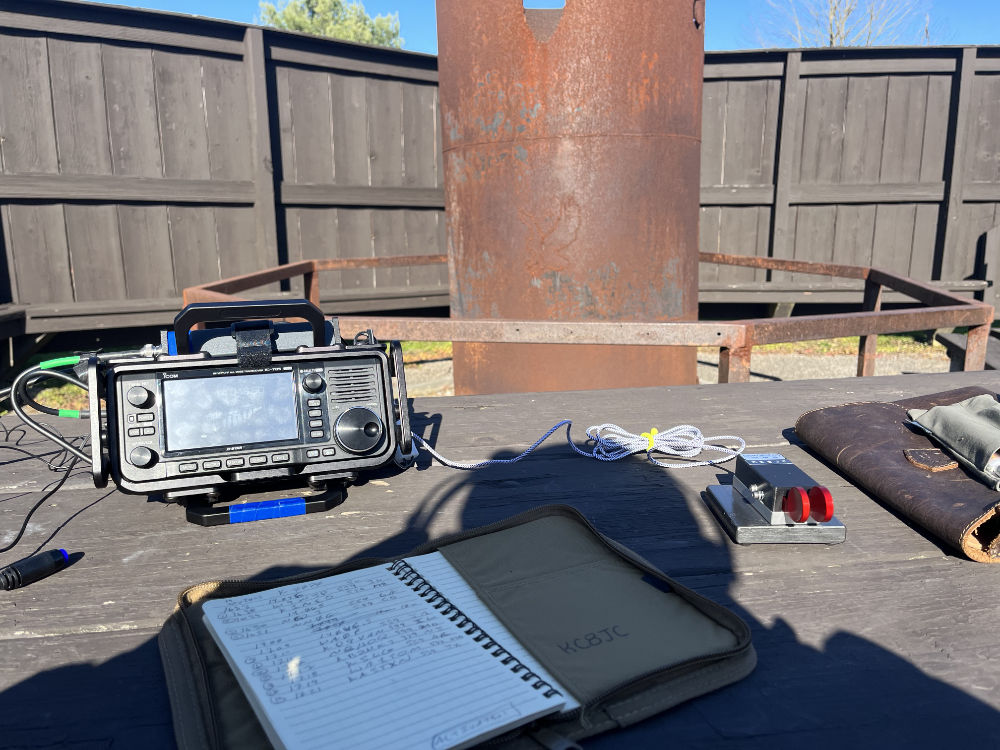 IC-705, log book, and paddles sitting on a picnic table in front of the fireplace.