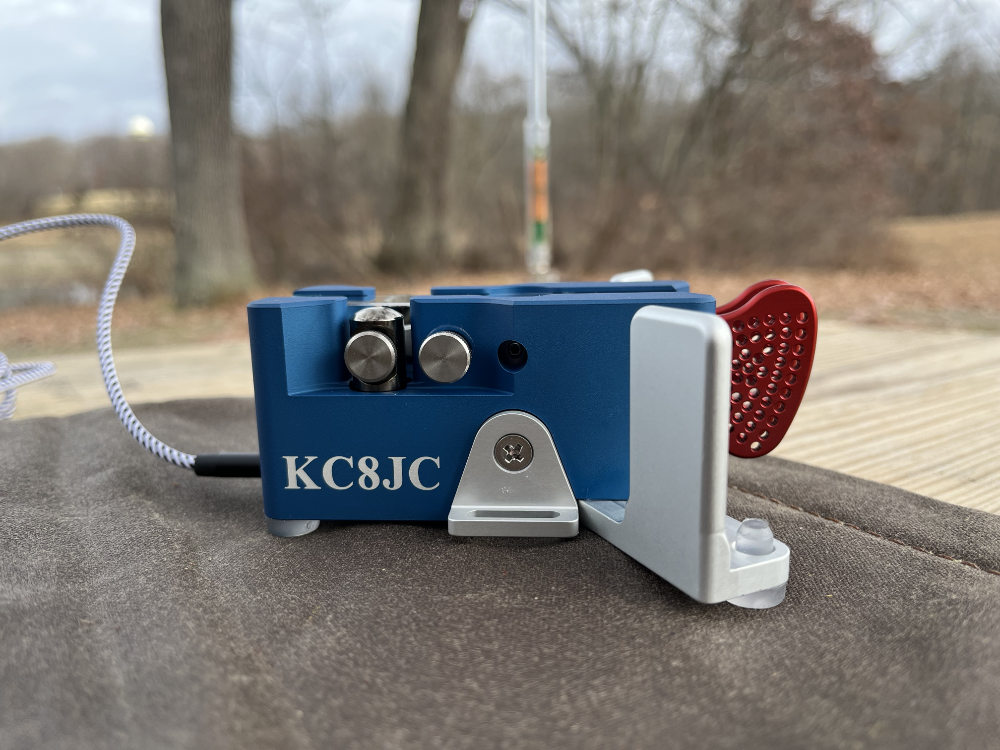 Begali Traveler Light key that is blue and has red paddles with KC8JC inscribed on the side.
