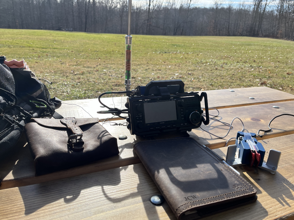 Leather bag next to my IC-705, log book, and paddles on a new standard issue picnic table.