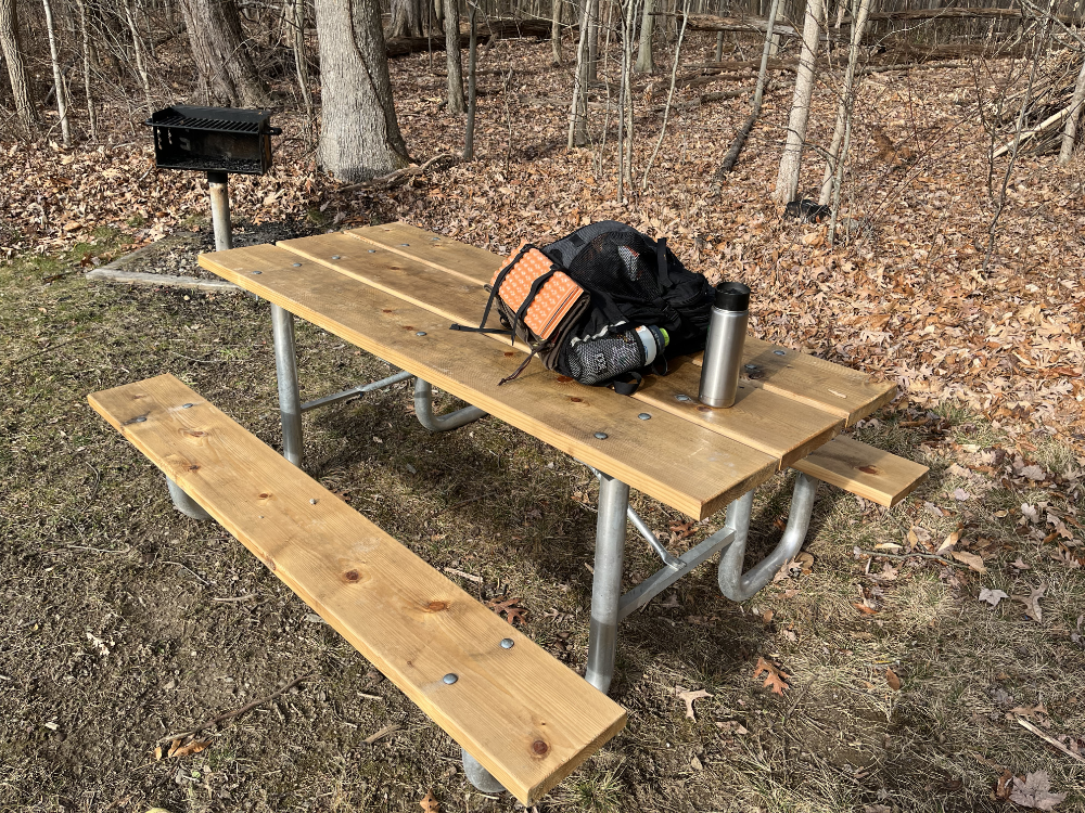 A new standard issue picnic table with a backpack resting on it.