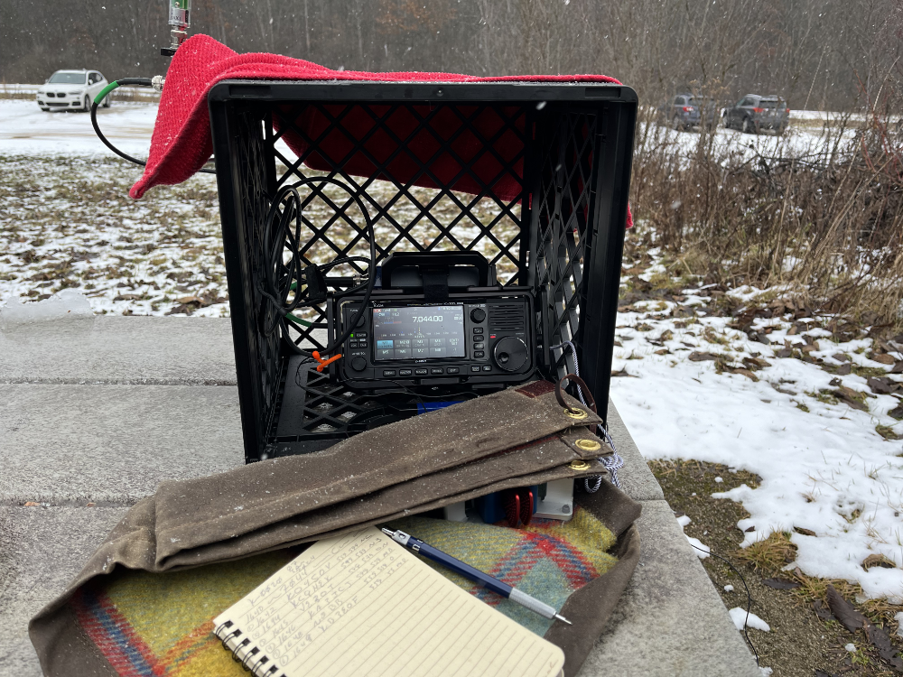 IC-705 in a crate with log book and paddles in the foreground.