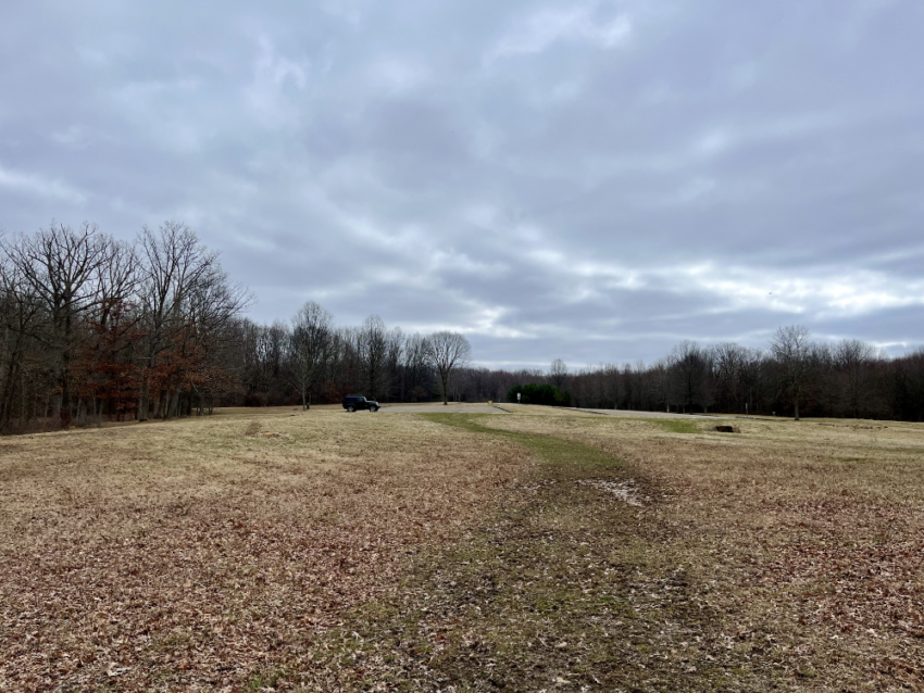 The open field and parking lot at West Branch State Park with a green Jeep in the distance.