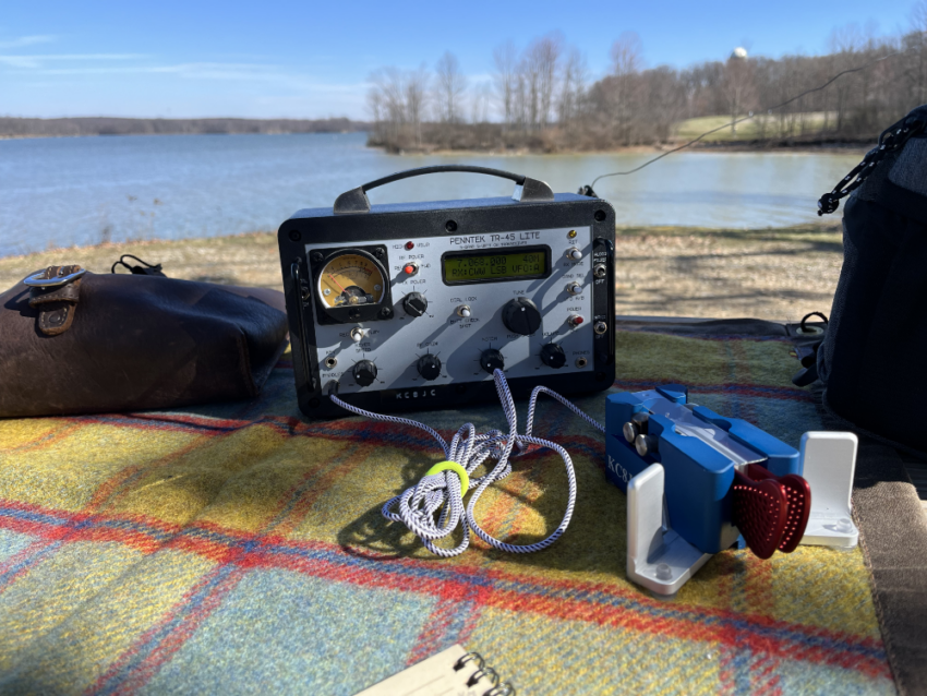 TR-45L radio on a picnic table next to Begali Traveller paddles and a log book.