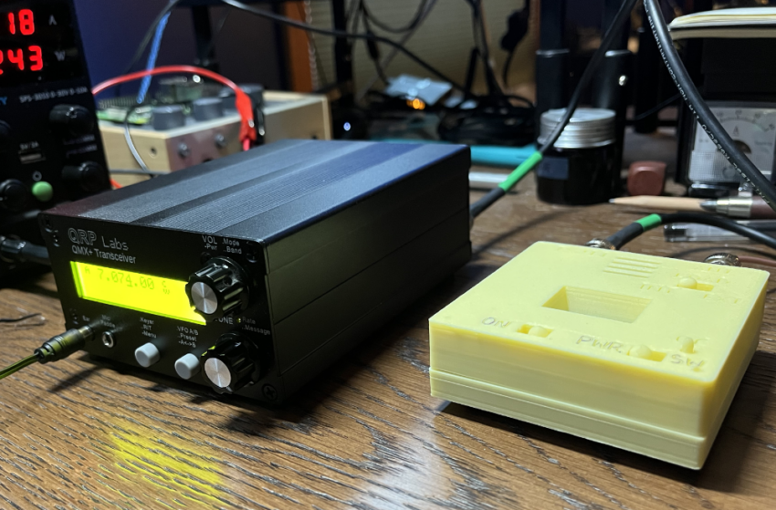 QMX+ on a desk next to a QRP SWR/Power meter.